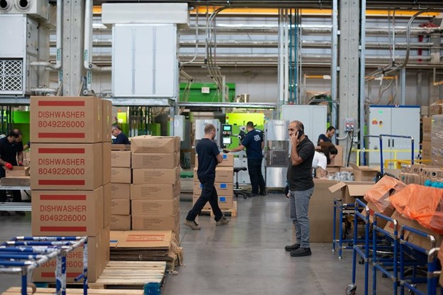 Man talking on the phone while people work in a factory around him